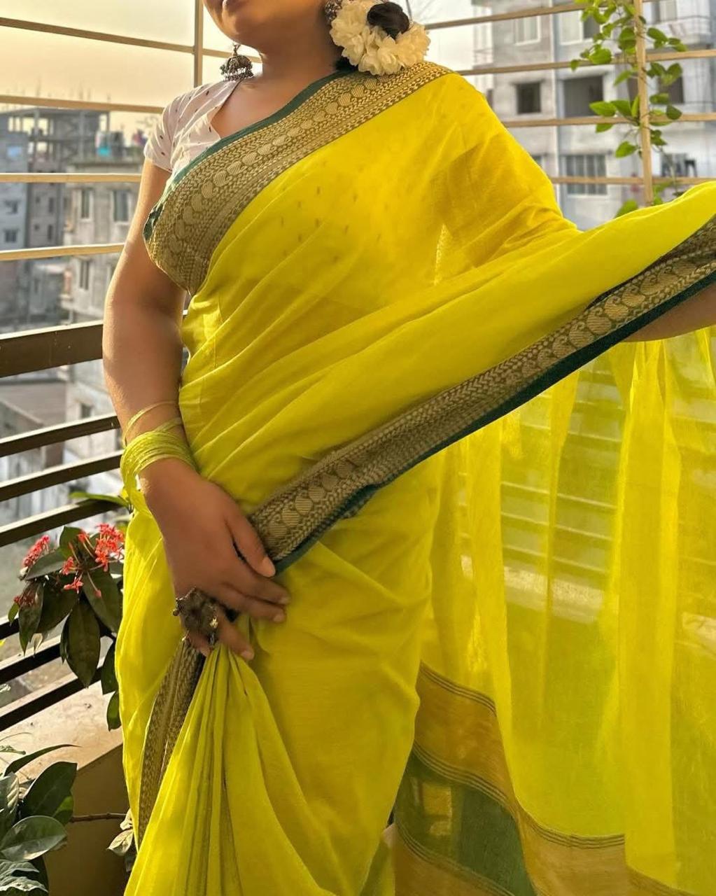 Roshni yellow mulmul saree with zari woven border — full drape on model balcony